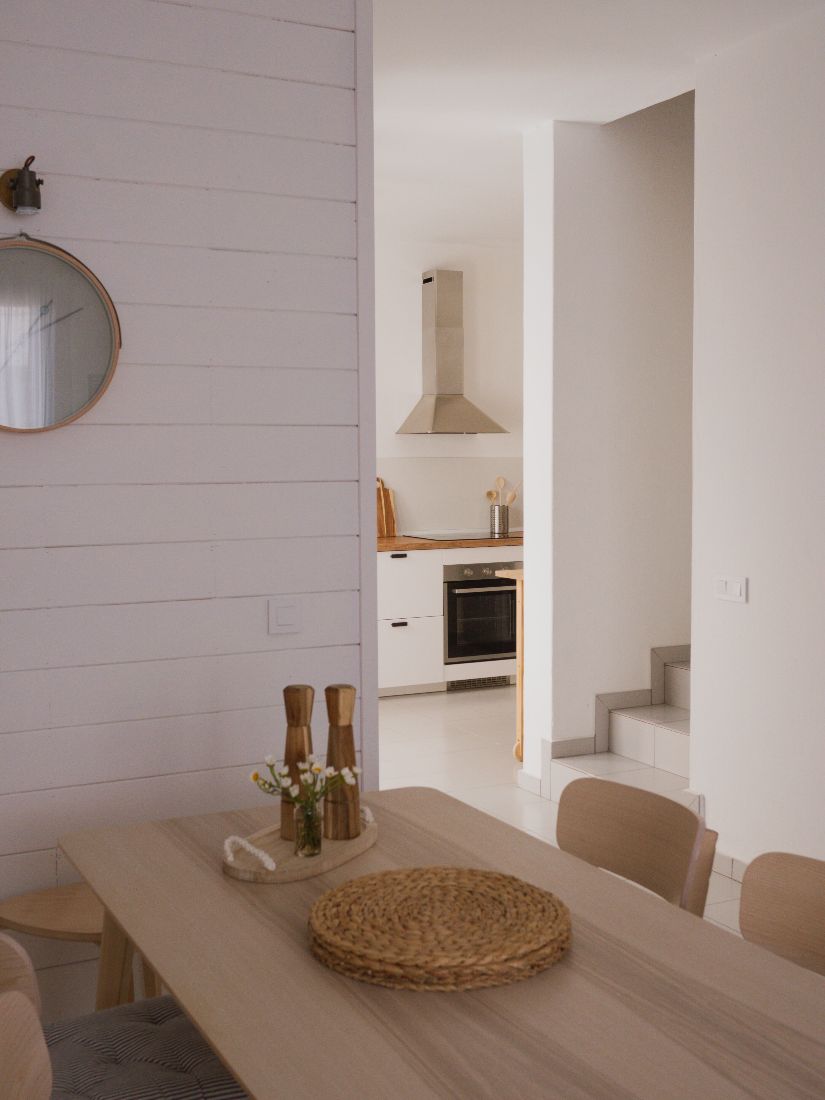 View past the shiplap wall and round mirror through to the kitchen