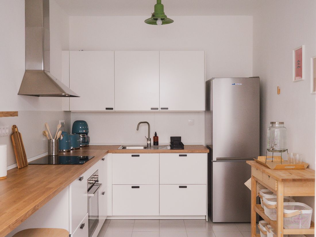 White kitchen with wood worktop, induction hob and fridge