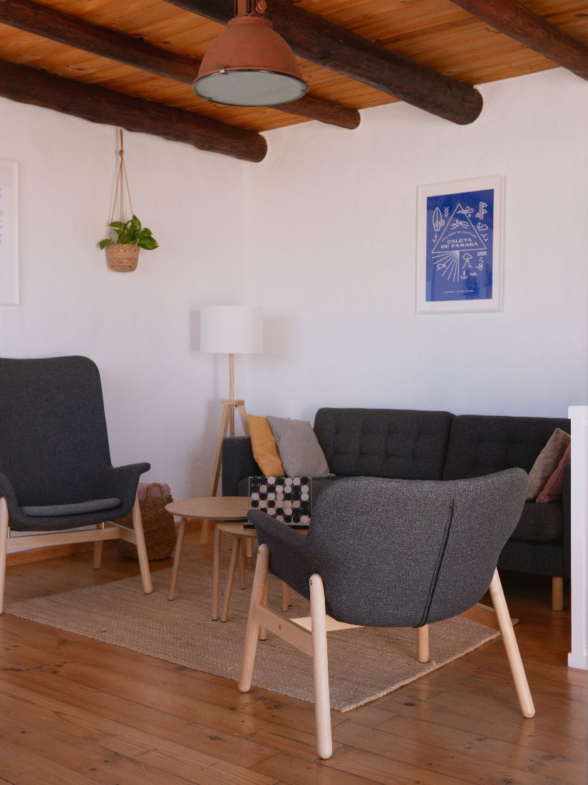 Living room with grey sofa, armchairs and a Caleta de Famara print