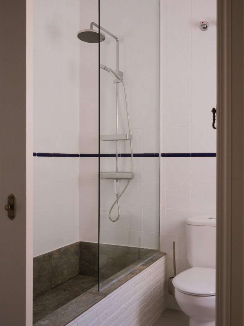 Walk-in stone shower behind a glass screen