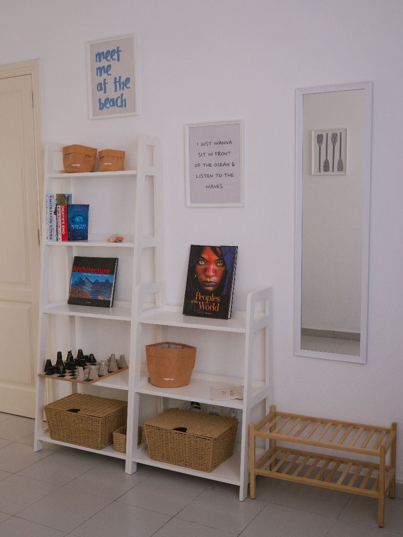 A white shelf of books, board games and travel reads by the door