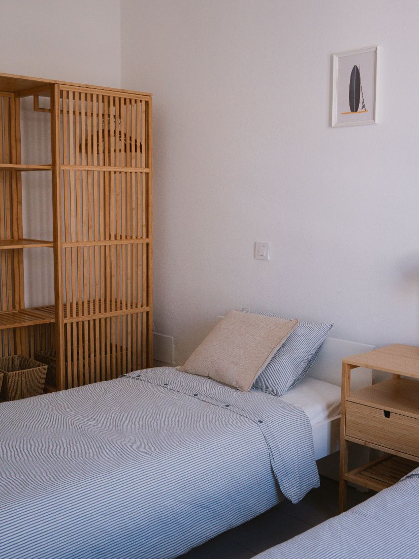 Twin room with striped linen and a bamboo room divider
